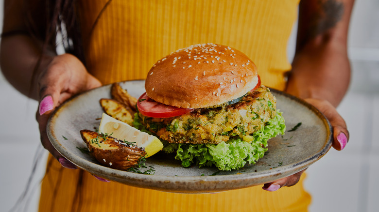 Person holding a plate with a vegan burger