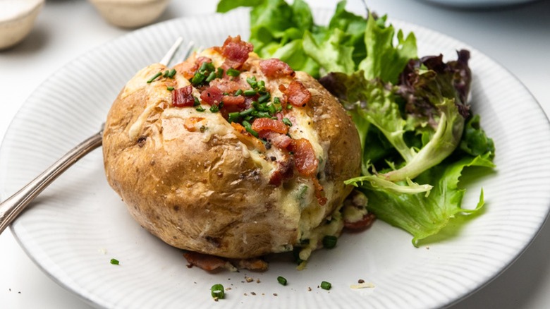 Loaded baked potato on plate with salad