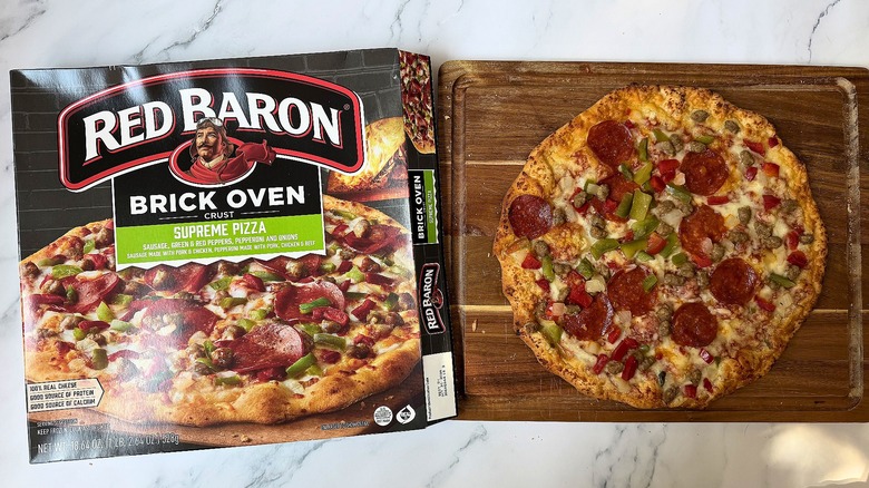 Red Baron Brick Oven Supreme pizza box next to pizza on cutting board