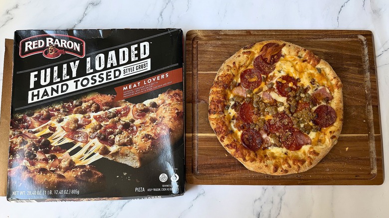 Red Baron Fully Loaded Hand Tossed Meat Lovers pizza box next to pizza on cutting board