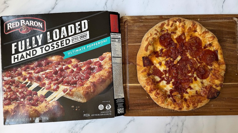 Red Baron Fully Loaded Hand Tossed Ultimate Pepperoni pizza box next to pizza on cutting board
