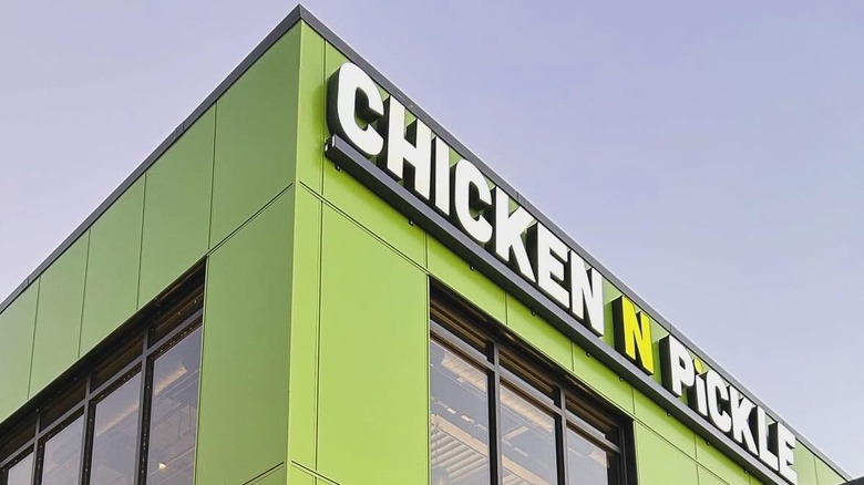 Chicken N Pickle sign on exterior of building against blue sky