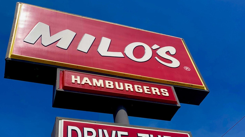 Sign for Milo's Hamburgers seen from a low angle on a cloudless day