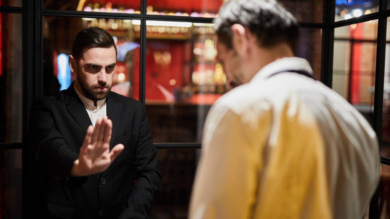 A restaurant staff member preventing a customer from entering the building