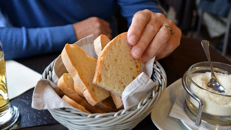 Man reaching for bread slice from a restaurant's bread basket