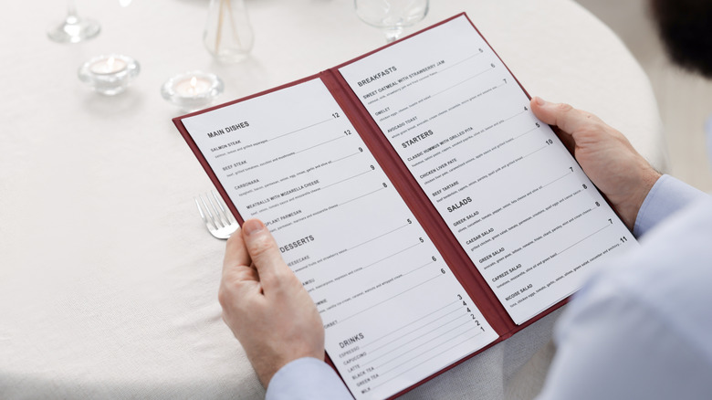 Closeup shot of a man with menu at table in restaurant