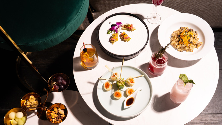 An overhead view of gourmet small plates placed on a white table