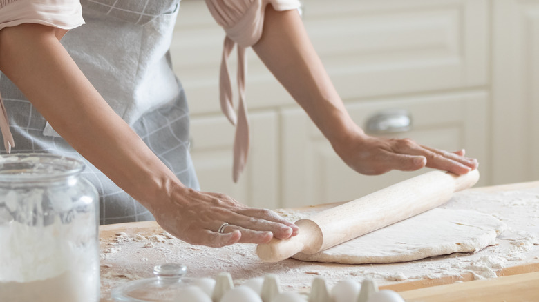 Person rolling dough with rolling pin