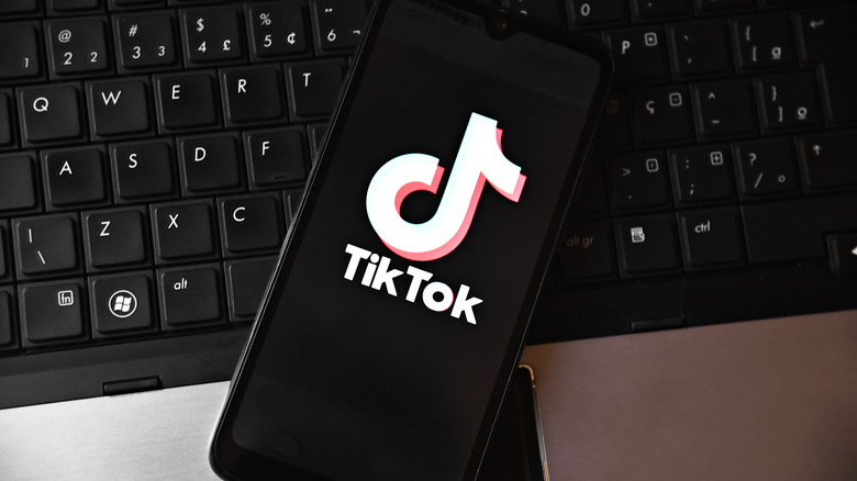phone with TikTok app logo on screen on top of a laptop keyboard