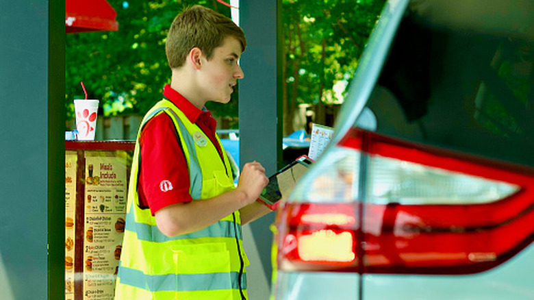 A Chick-fil-A employee takes a customer's order at the drive through