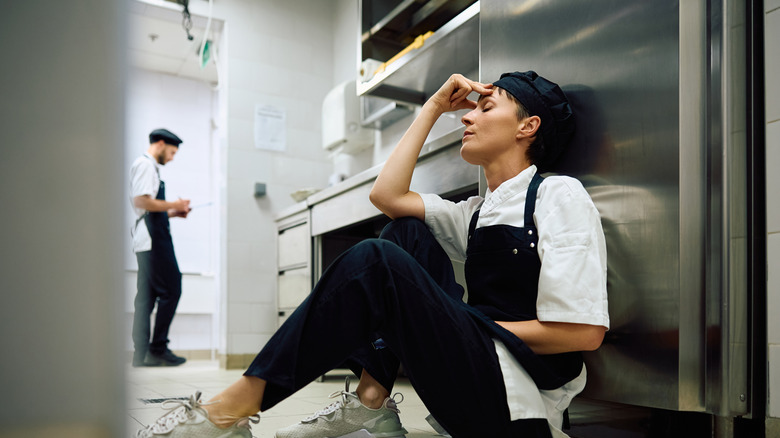 stressed out chef sat on the floor in the kitchen