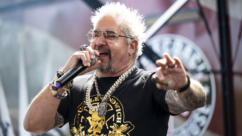 Guy Fieri speaks into microphone on stage