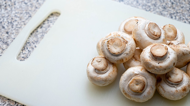White mushrooms placed on a silicone cutting board
