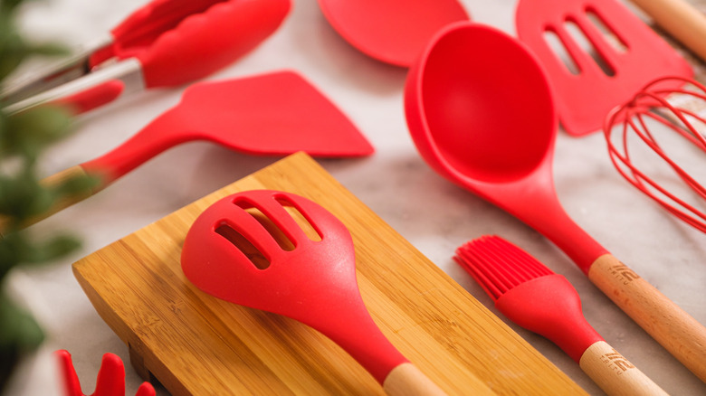Several red silicone spatulas with wooden handles laid out in a kitchen