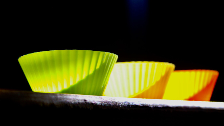 A set of three colored silicone cupcake molds in sunlight