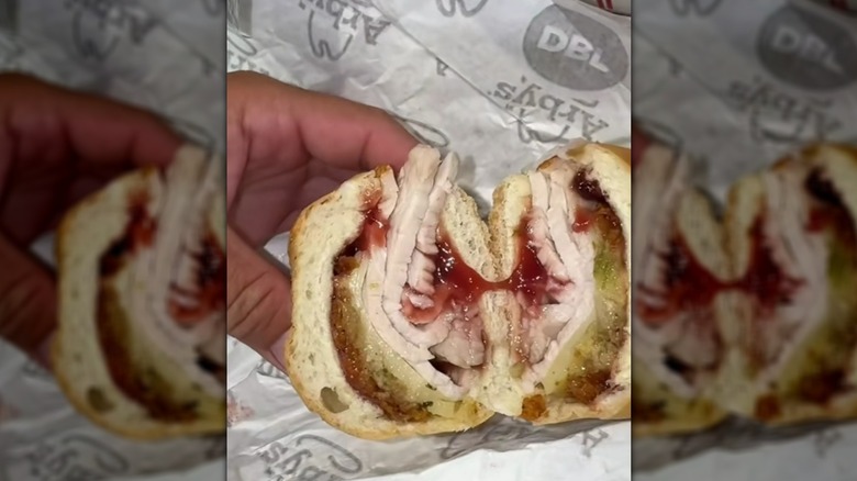 Hand holding halved deep-fried turkey sandwich from Arby's