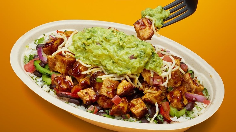 Fork digging into Chipotle rice bowl with honey chicken and guacamole