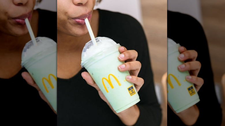 Person sipping Mcdonald's Shamrock Shake in a plastic cup with a straw