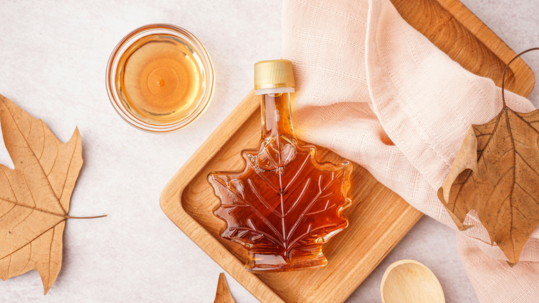 Bottle of maple syrup surrounded by maple leaves
