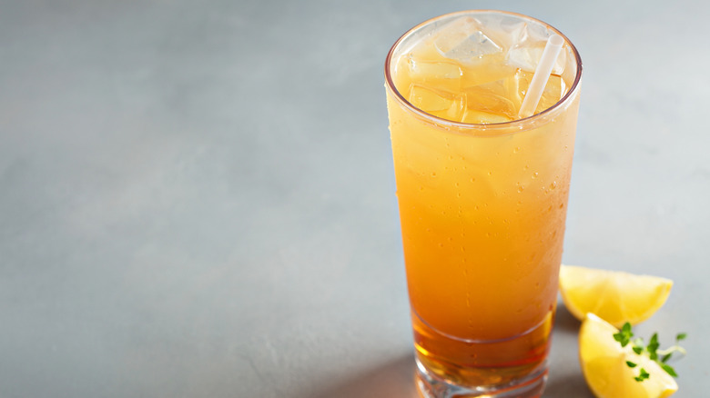 The Arnold Palmer drink in a glass with lemon on the side