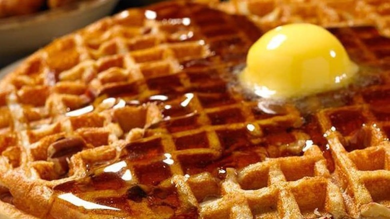 A cooked waffle with syrup and butter melting