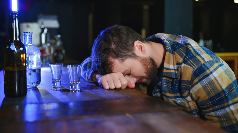A man falling asleep on a bar counter