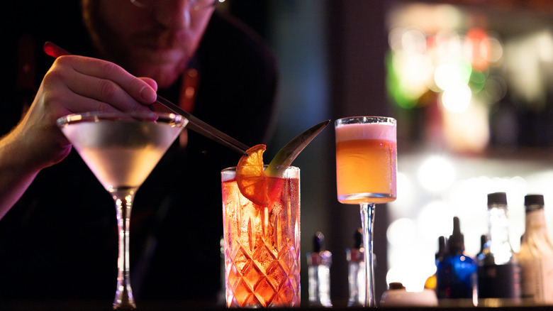A bartender serving some fancy cocktails with garnishes