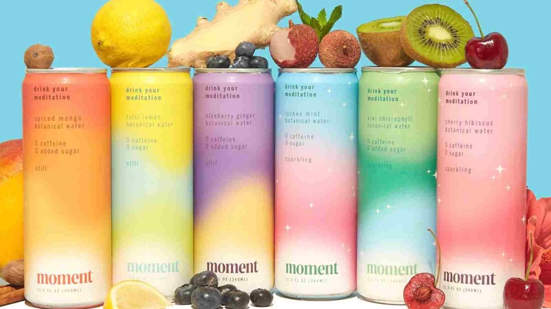 Several cans of Moment displayed alongside fruits