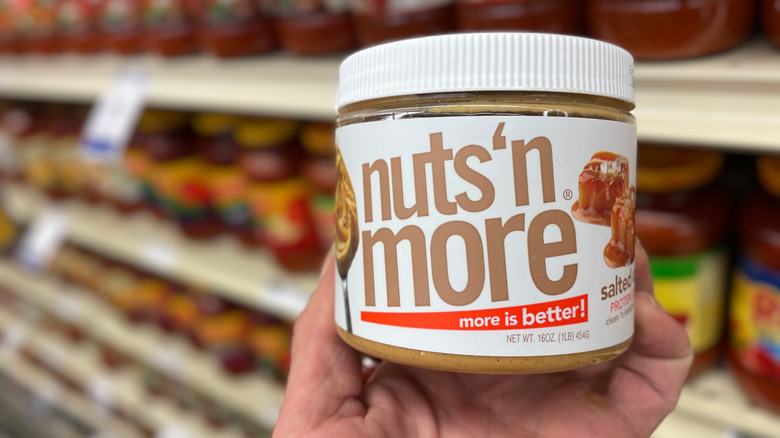 Hand holding a jar of Nuts 'n More at a grocery store