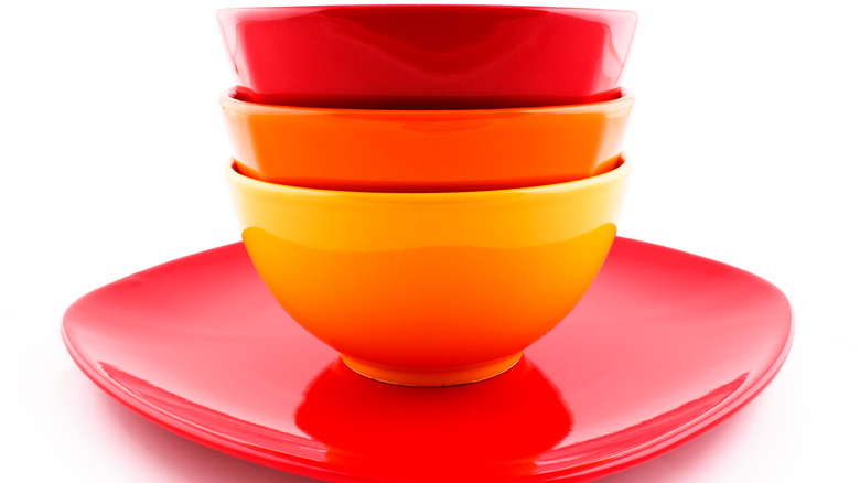 Red, orange, and yellow bowls on a square red plate