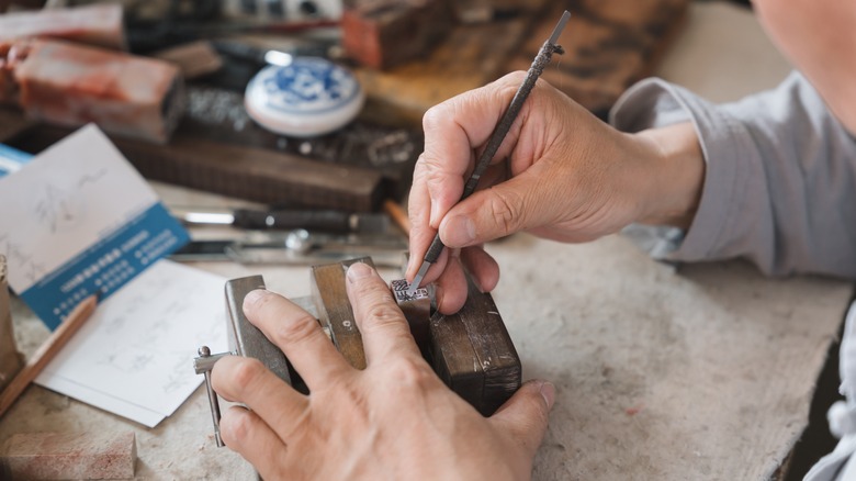 A person working on a metal object in a vice grip