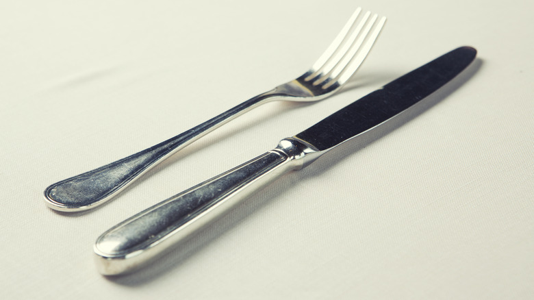 A silver knife and fork on a cream tablecloth