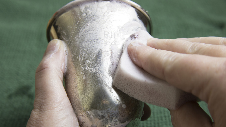 A hand polishing a silver goblet