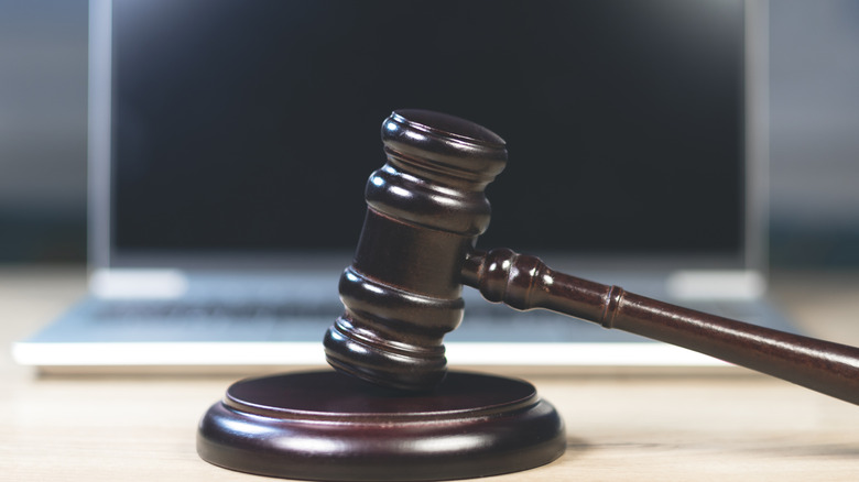 An auctioneer gavel in front of a silver computer