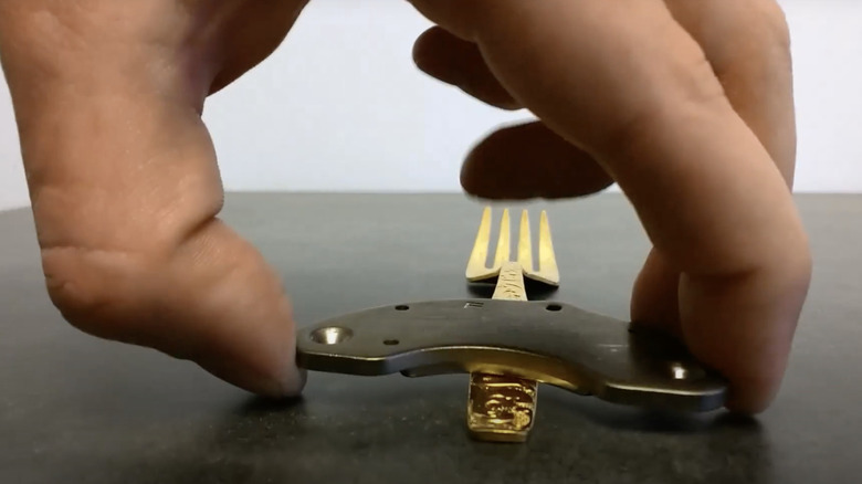 A hand using a magnet on silverware