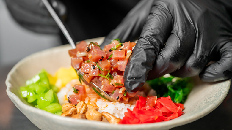 Gloved hand plating ceviche in bowl