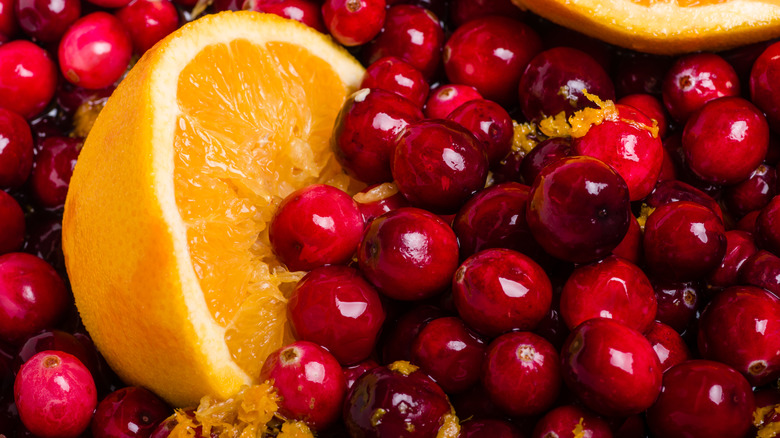 Half of an orange sitting on fresh cranberries
