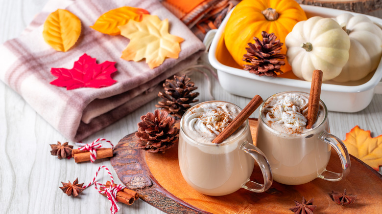 A festive fall scene with pumpkin spice lattes, cinnamon, pumpkins, and leaves