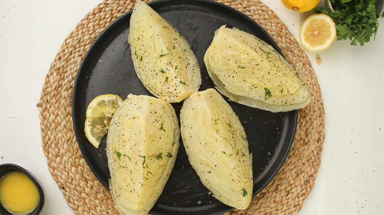 Boiled cabbage wedges on plate, sprinkled with black pepper
