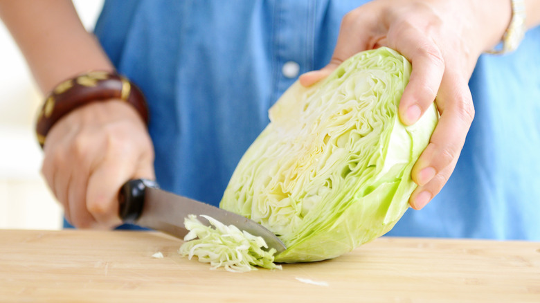 Chopping white cabbage on wooden cutting board
