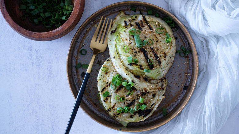 Scallion-topped cabbage steaks on plate with fork