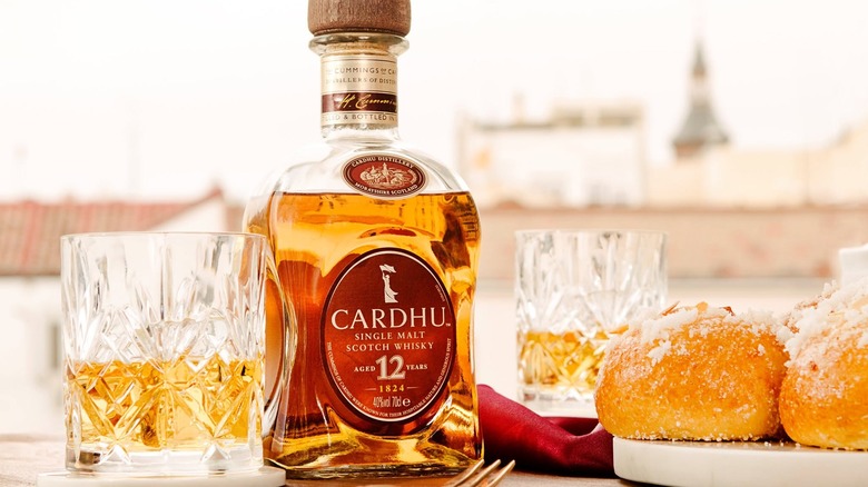 A bottle of Cardhu 12-year with filled glasses either side and next to food
