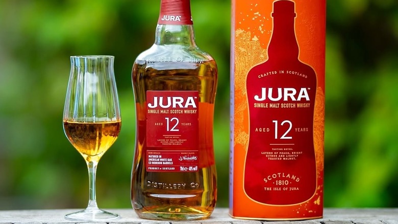 A bottle of Jura 12-year surrounded by a filled glass and its packaging