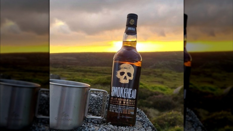 A bottle of Smokehead Original placed on a rock in a natural setting