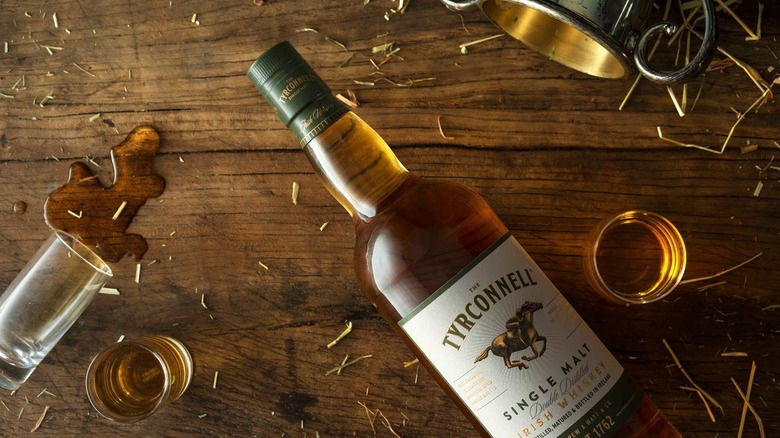 A top down shot of Tyrconnell Single Malt laid down on a wooden surface surrounded by glasses