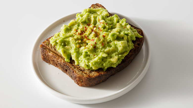 Smashed avocado toast on white plate
