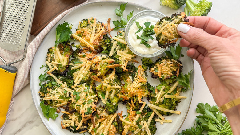 Plate of crispy smashed broccoli with creamy dip and fresh herb garnish