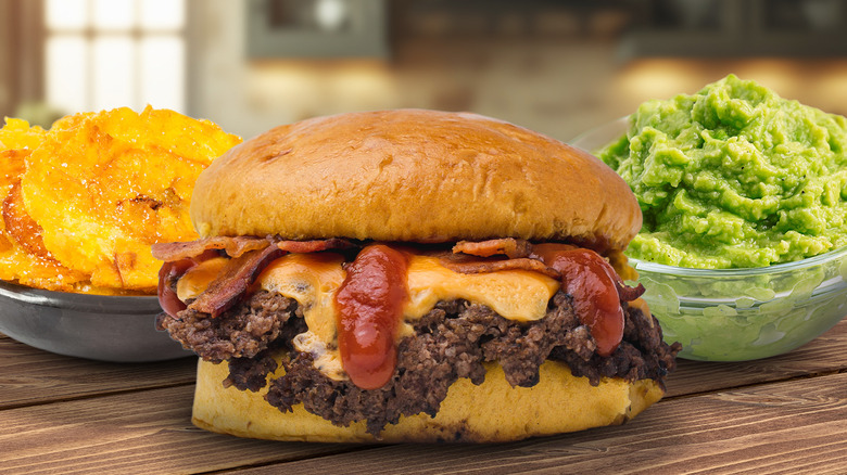 Composite image of a bowl of smashed potatoes, a smash burger, and a bowl of smashed avocado on a wood table