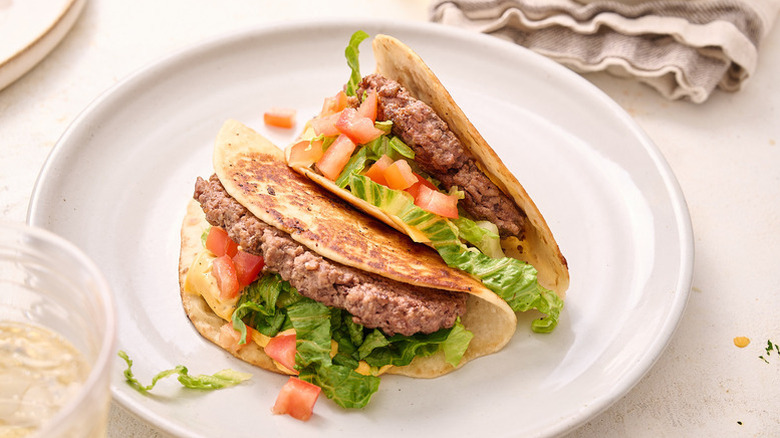Two smash burger tacos on white plate