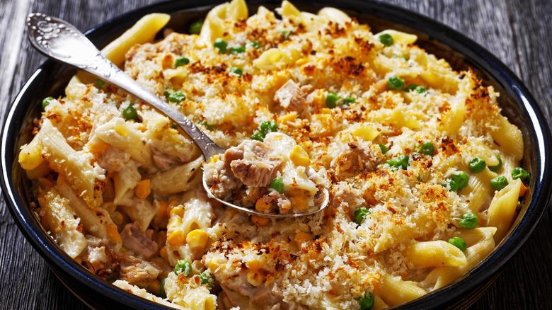 Tuna Casserole Penne Pasta Bake in black dish on dark wooden table with spoon